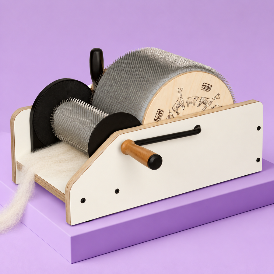 Louët drum carder with ivory wool feeding beneath the smaller drum, on a lavender platform.