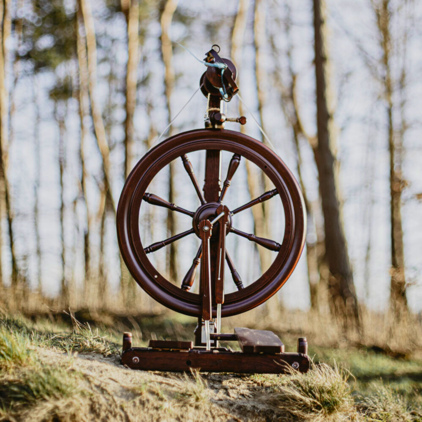 Kromski Sonata Encore spinning wheel outdoors in a woodland setting—portable folding wheel for travel-friendly handspinning.