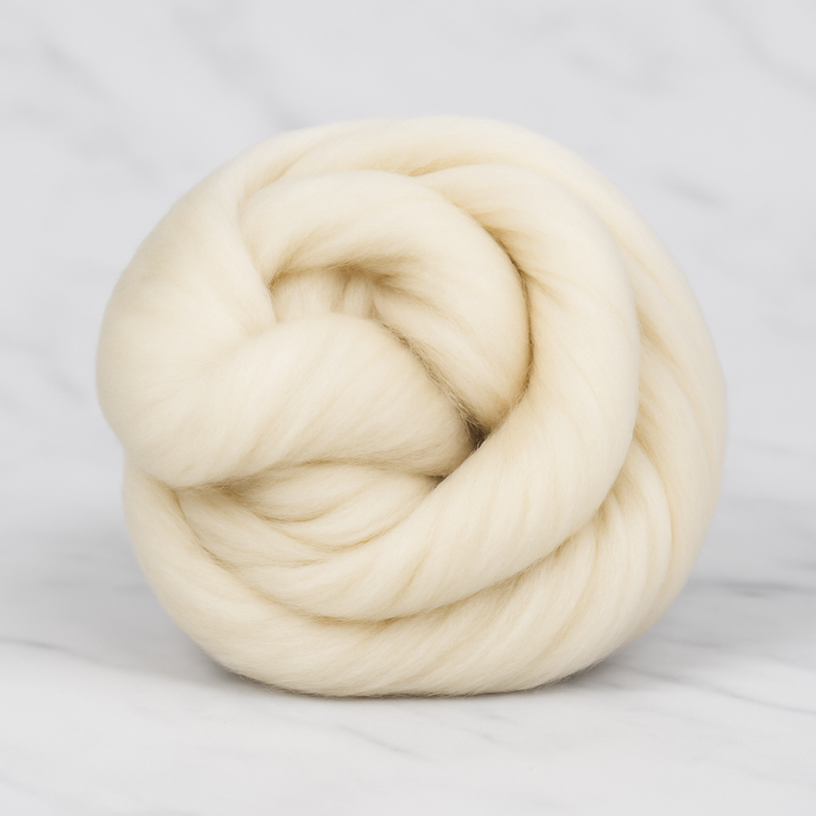 High-resolution photo of undyed Rambouillet combed wool top in ecru, styled as a coiled bundle on marble background.