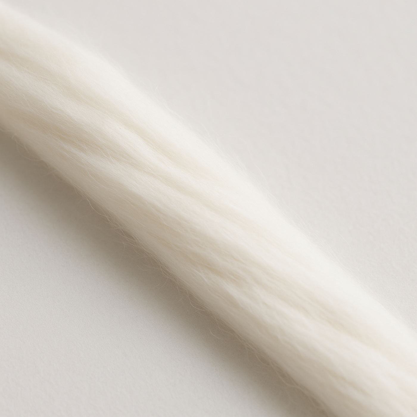 Single strand close-up of undyed Merino roving—soft, smooth fiber ideal for needle felting and wet felting.