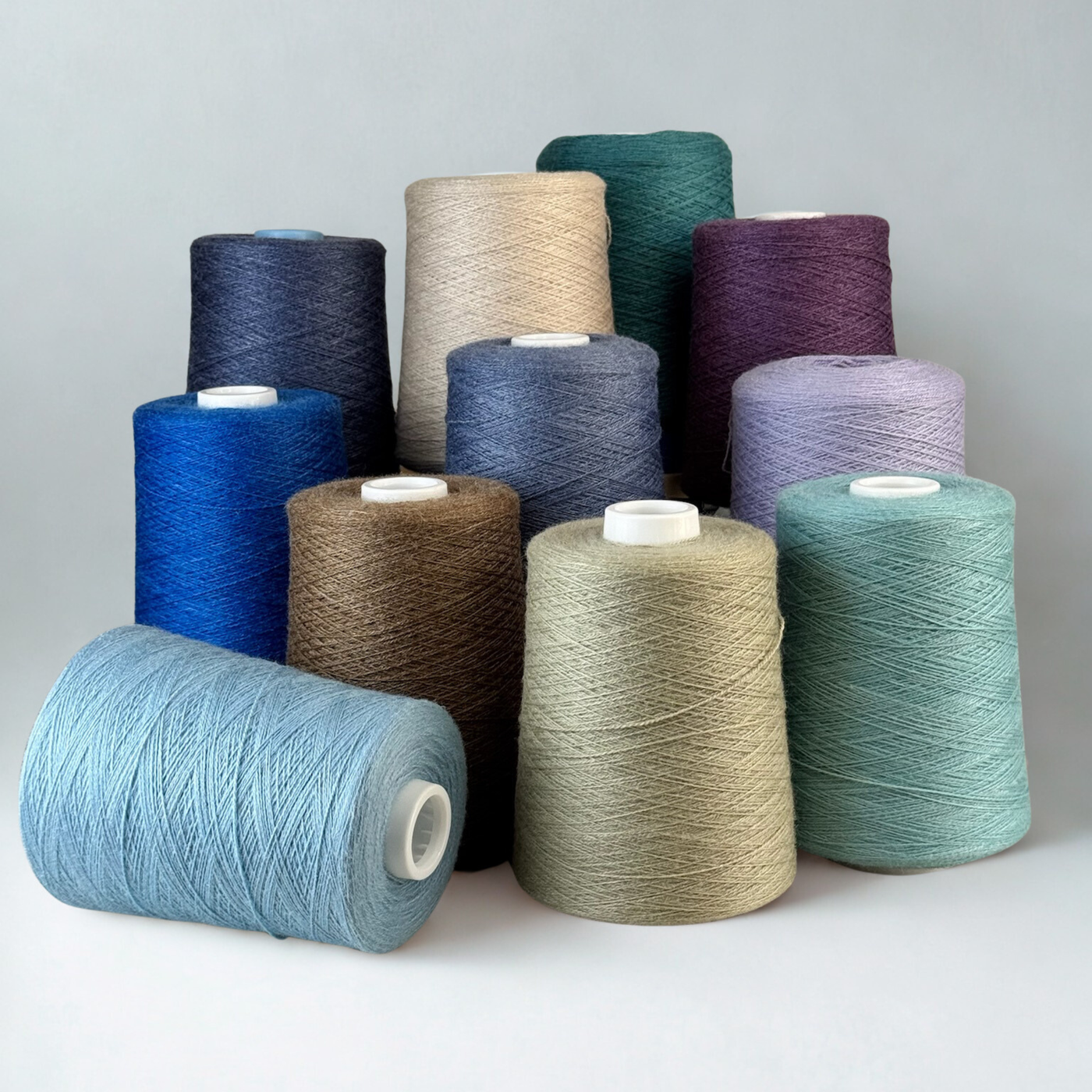 Assorted cones in cool and neutral tones against white; 1 lb. cones, 2/18 lace, 4455 yards—silky hand and dependable drape.