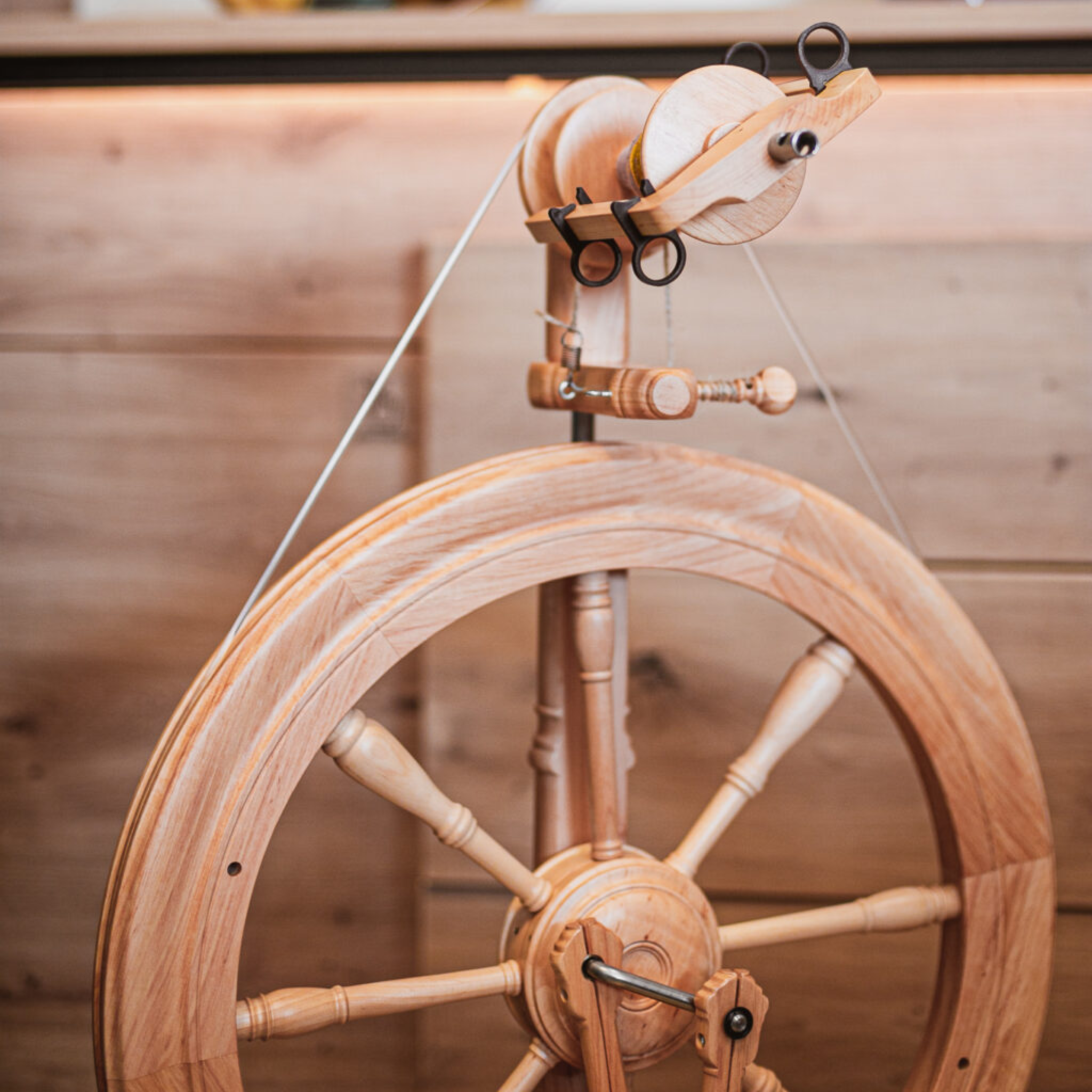 Close-up of Kromski Sonata Encore drive wheel and flyer, showing balanced spokes and travel wheel proportions in natural wood.