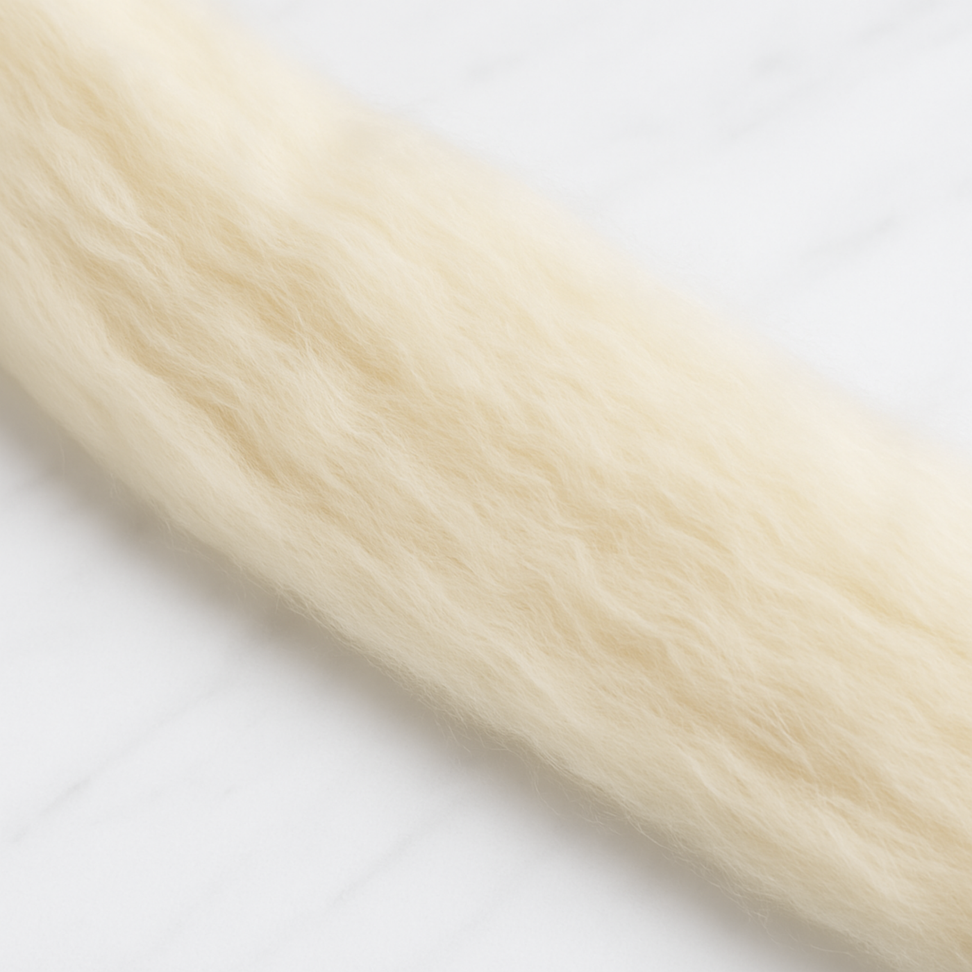 Close-up of natural Rambouillet wool fibers showing fine crimp and airy texture, ideal for spinning or felting.