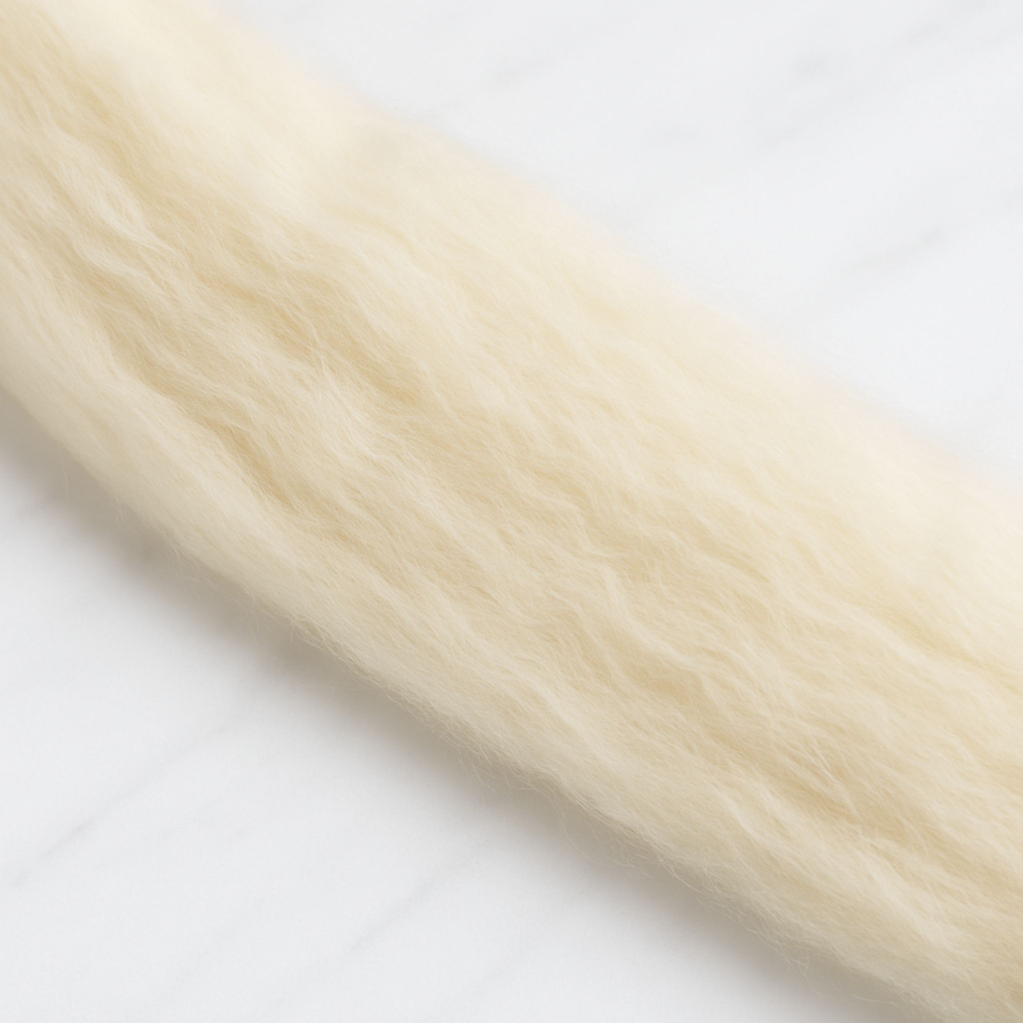 Close-up of natural Rambouillet wool fibers showing fine crimp and airy texture, ideal for spinning or felting.
