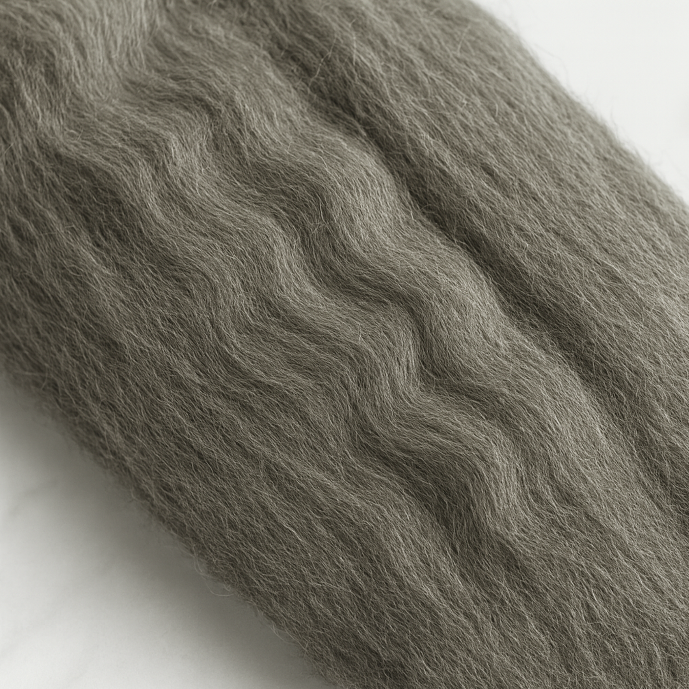 Close-up of Corriedale combed top showing even crimp and aligned 28-micron fibers—natural gray, undyed wool for smooth drafting.