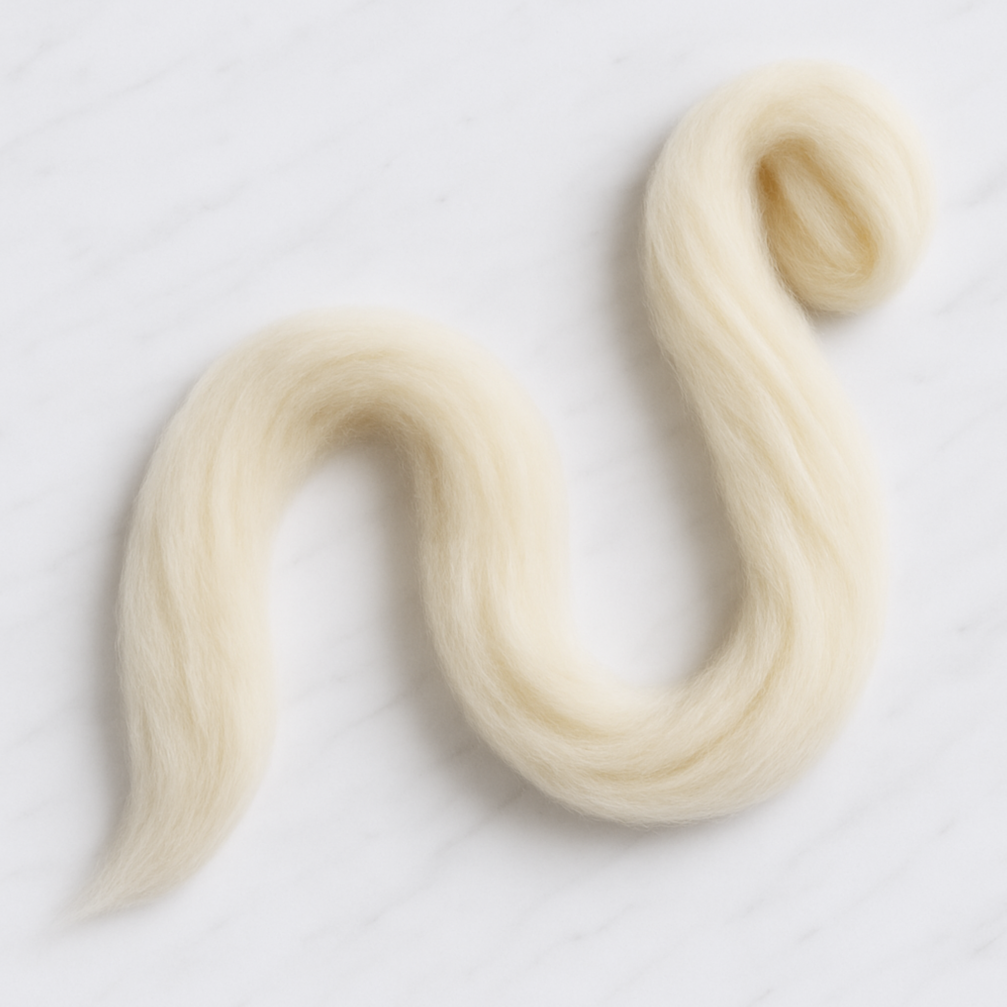 Loose length of Rambouillet combed top stretched out in natural curves across marble surface.