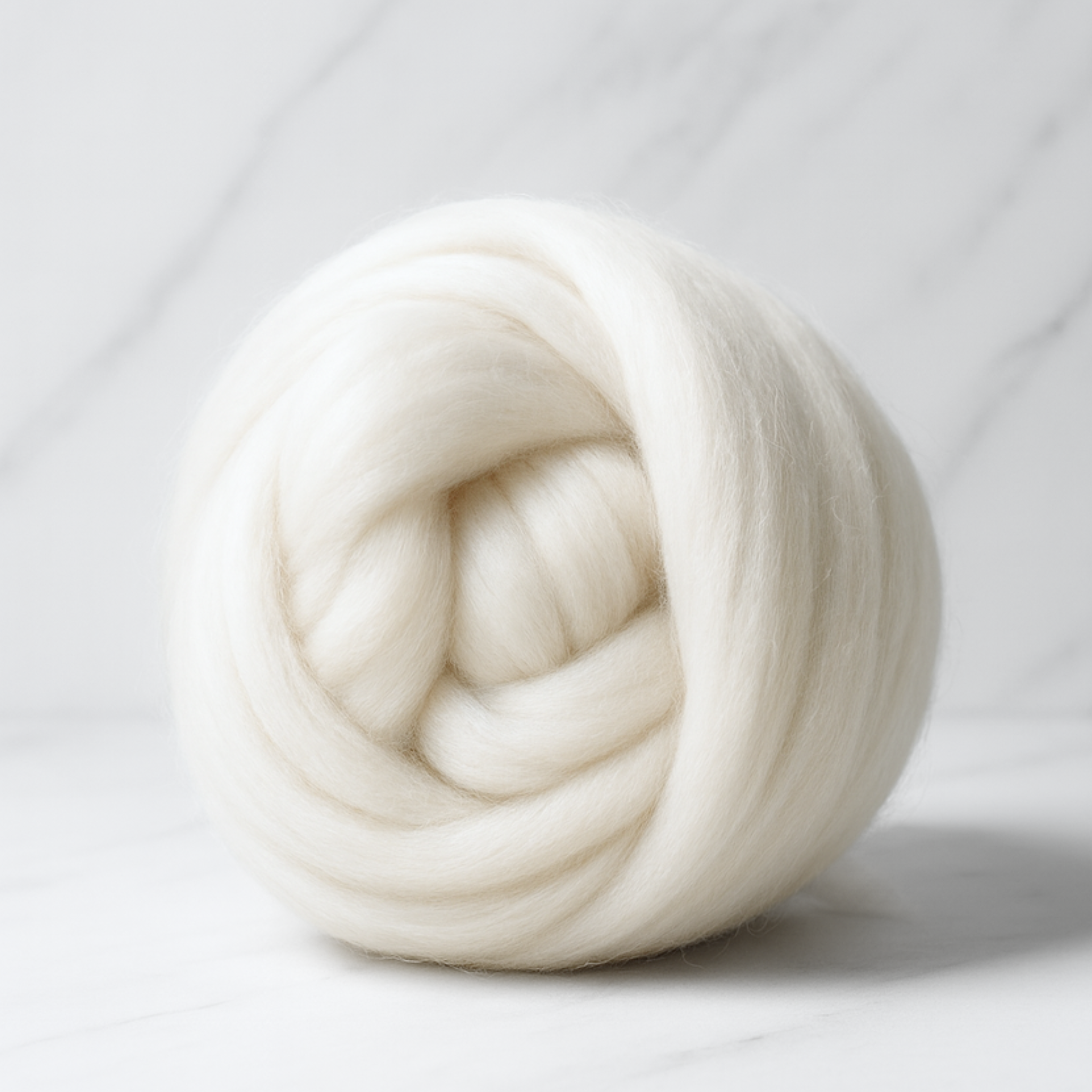 Small coiled nest of undyed Merino roving—fine, consistent preparation for beginner-friendly spinning and blending.