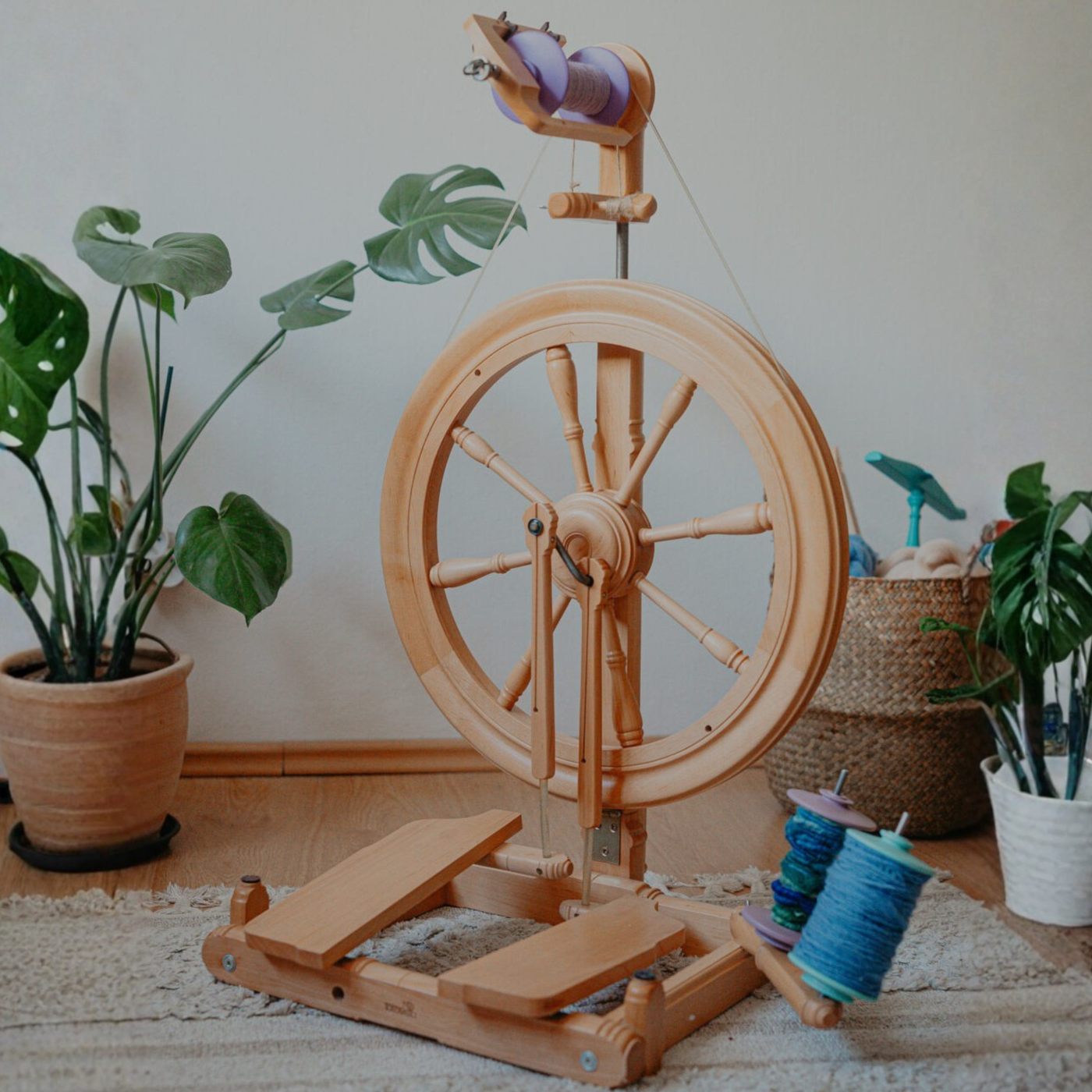 Kromski Sonata Encore spinning wheel staged at home with plants and blue yarn, a modern setup for smooth, quiet handspinning.