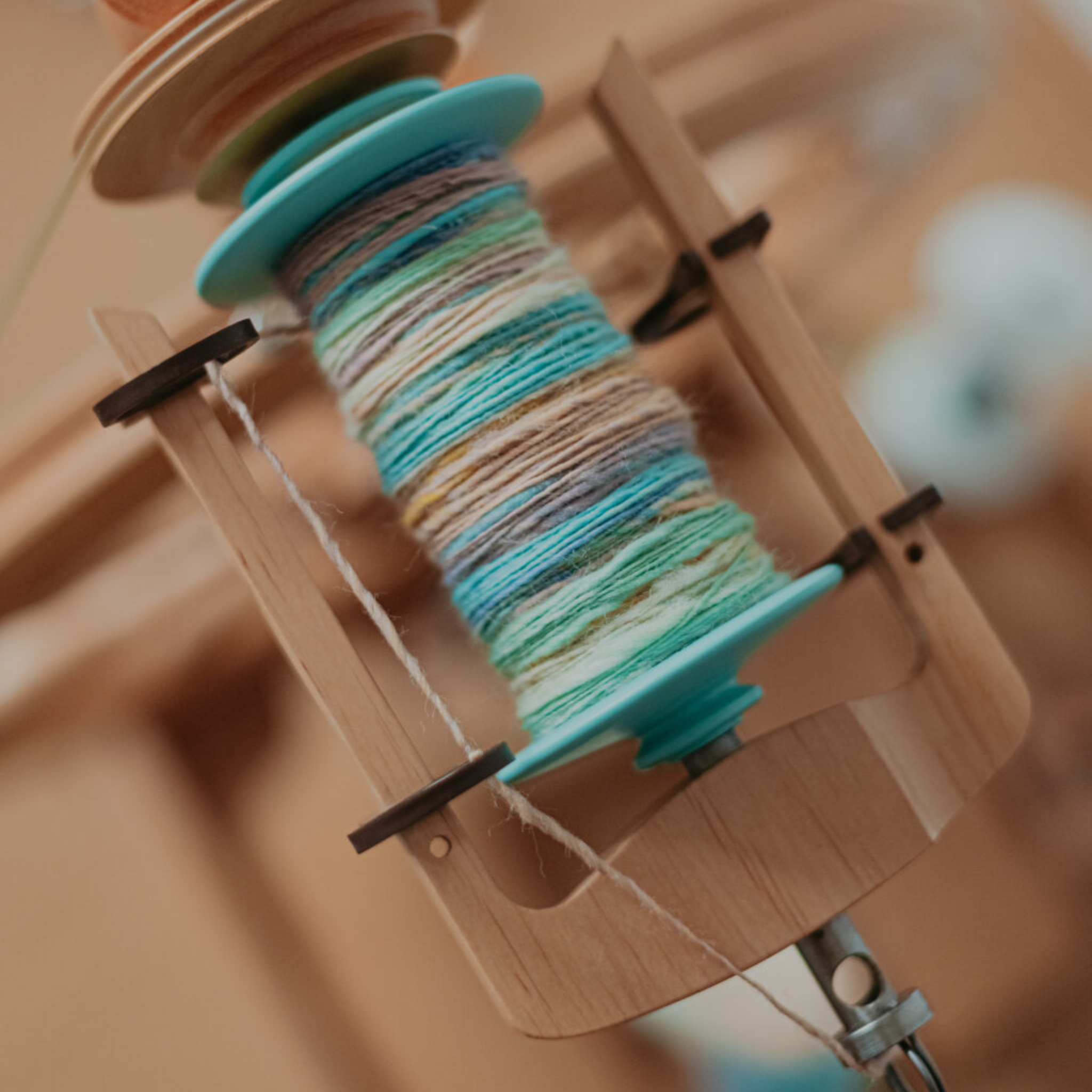 Macro close-up of Kromski Sonata flyer and bobbin with handspun turquoise yarn, showing even winding and smooth take-up.