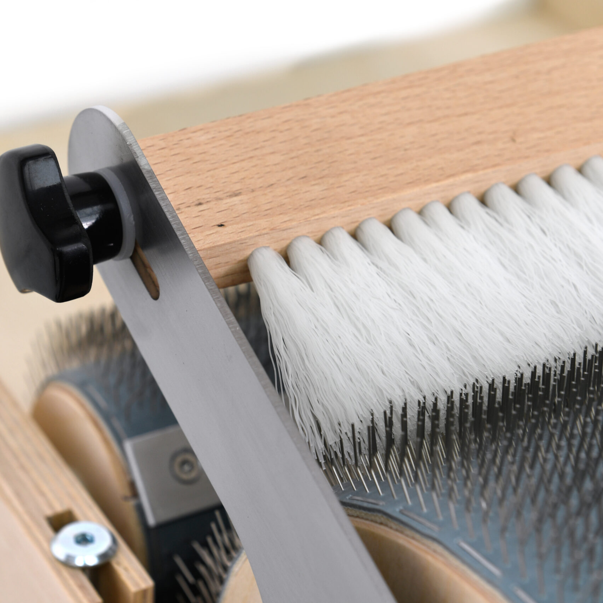 Detail of the Golden Fleece Packer Brush, metal mounting bracket, adjustment knob, and white brush fibers.