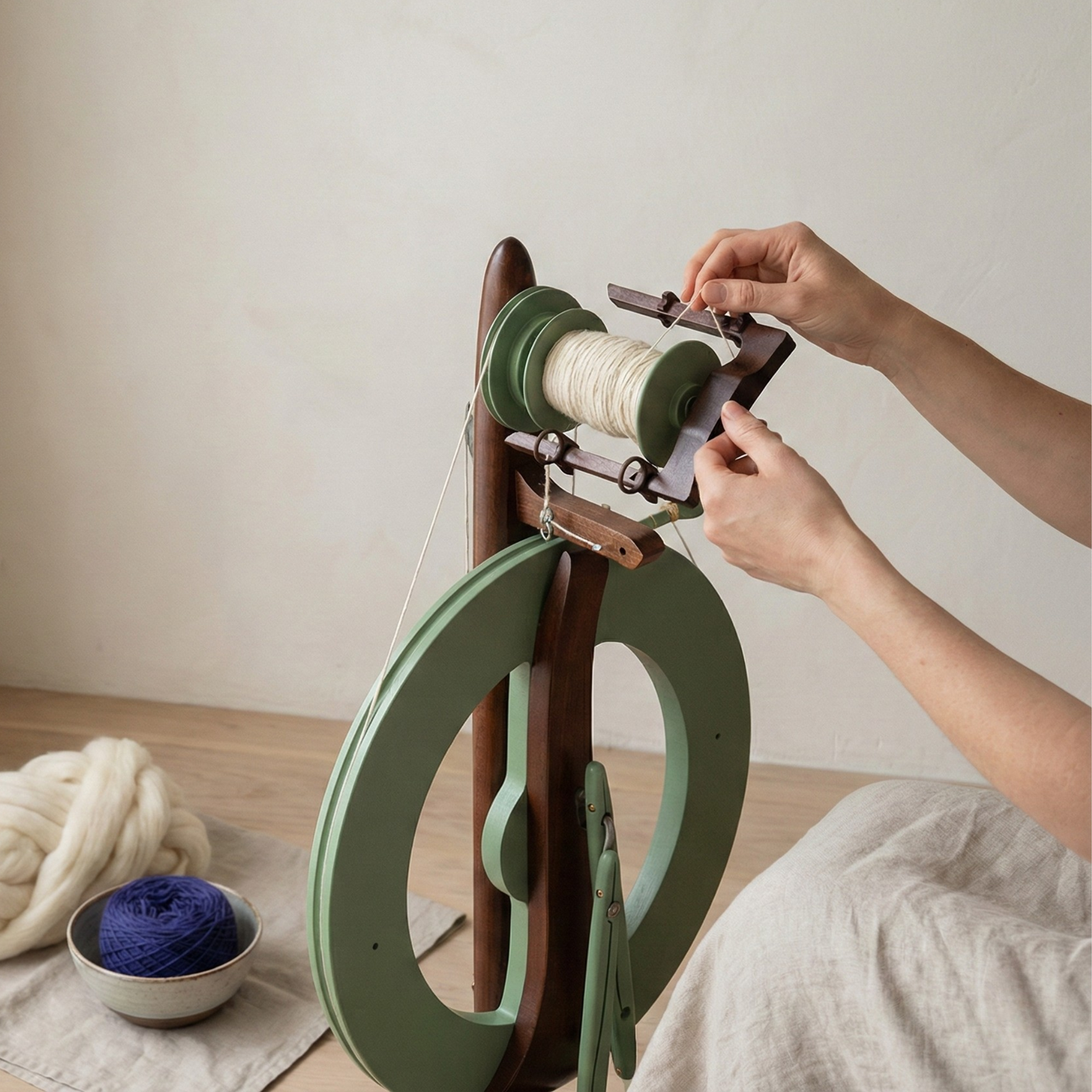 A maker spinning yarn on the limited edition Kromski Fantasia in meadow green with walnut accents. In a calm windowlite studio.