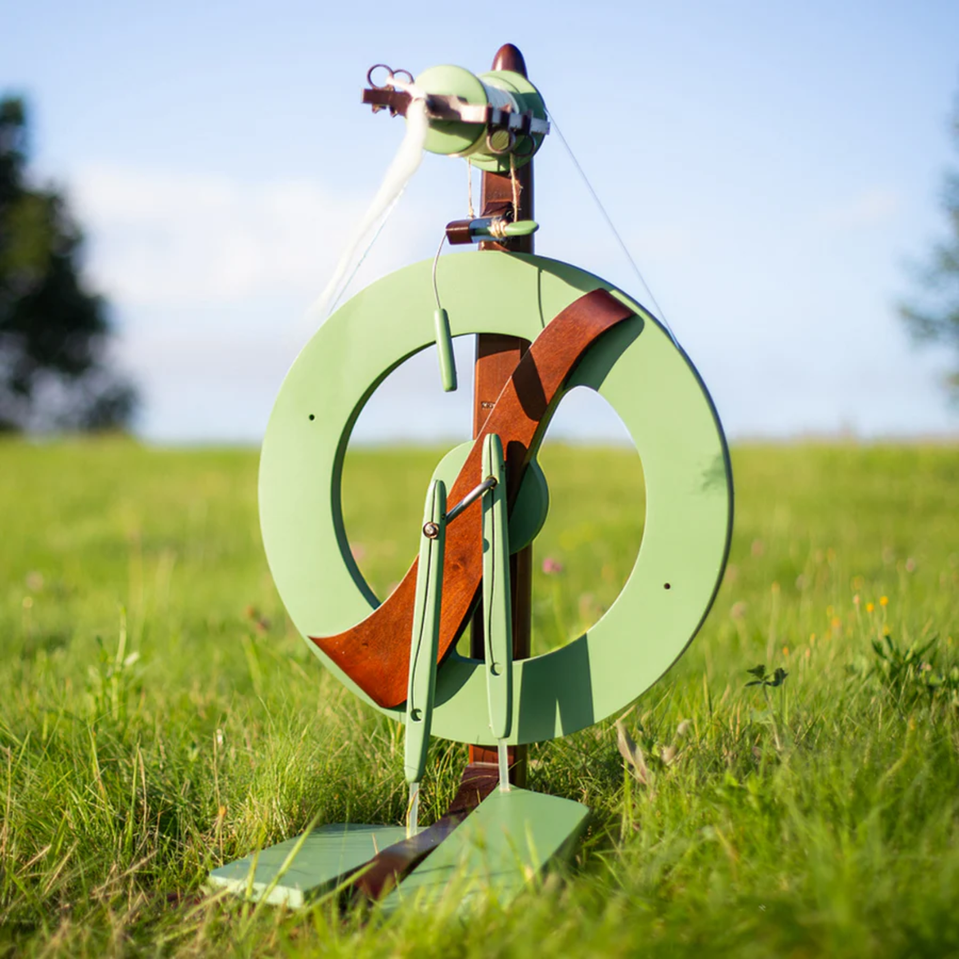 The Kromski Fantasia Limited Edition Meadow Green Spinning Wheel outdoors in  meadow setting.