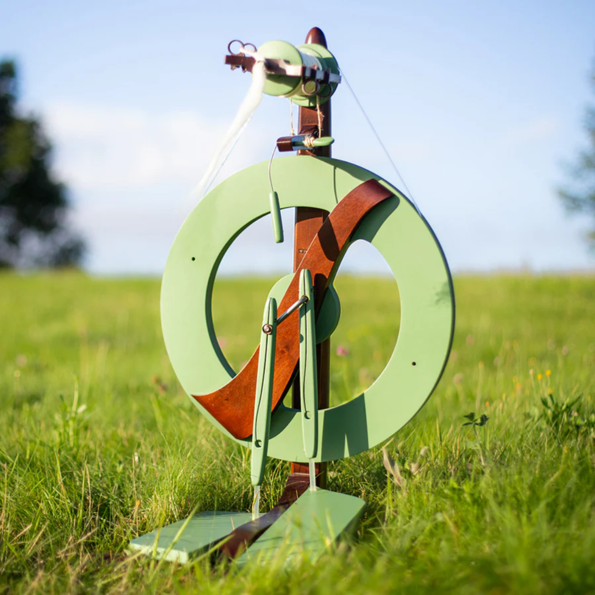 The Kromski Fantasia Limited Edition Meadow Green Spinning Wheel outdoors in  meadow setting.