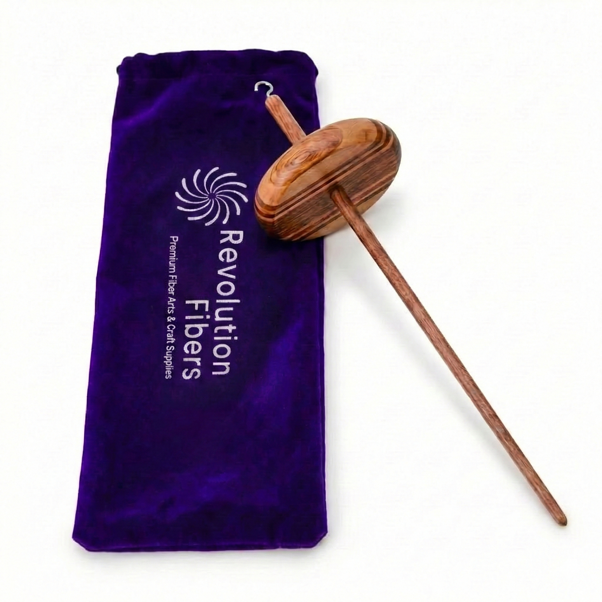 What’s included: Revolution Fibers top whorl drop spindle and purple velvet carrying case shown together on a clean white background