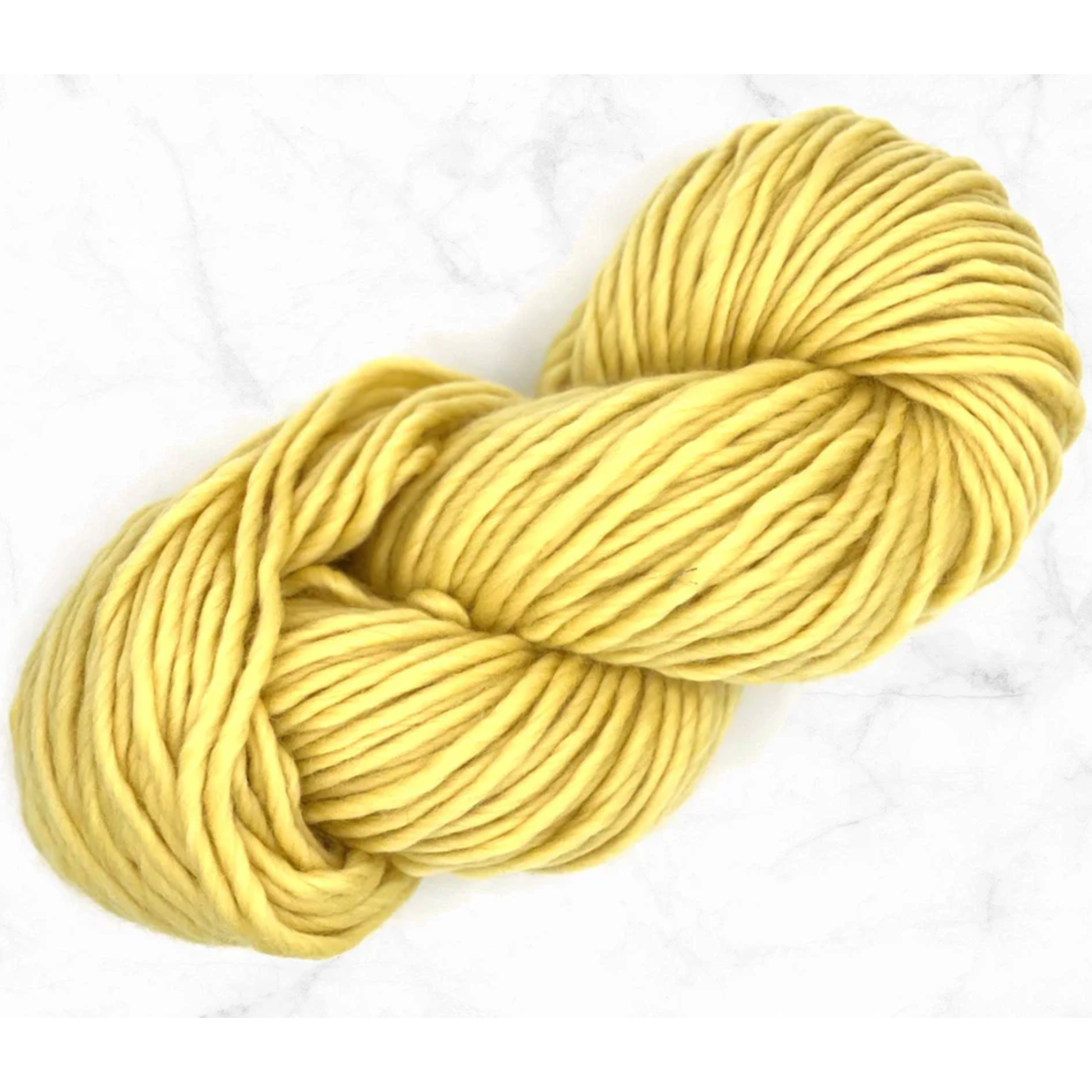 A bright pastel yellow super bulky weight skein of catkin merino wool yarn on a marble background.