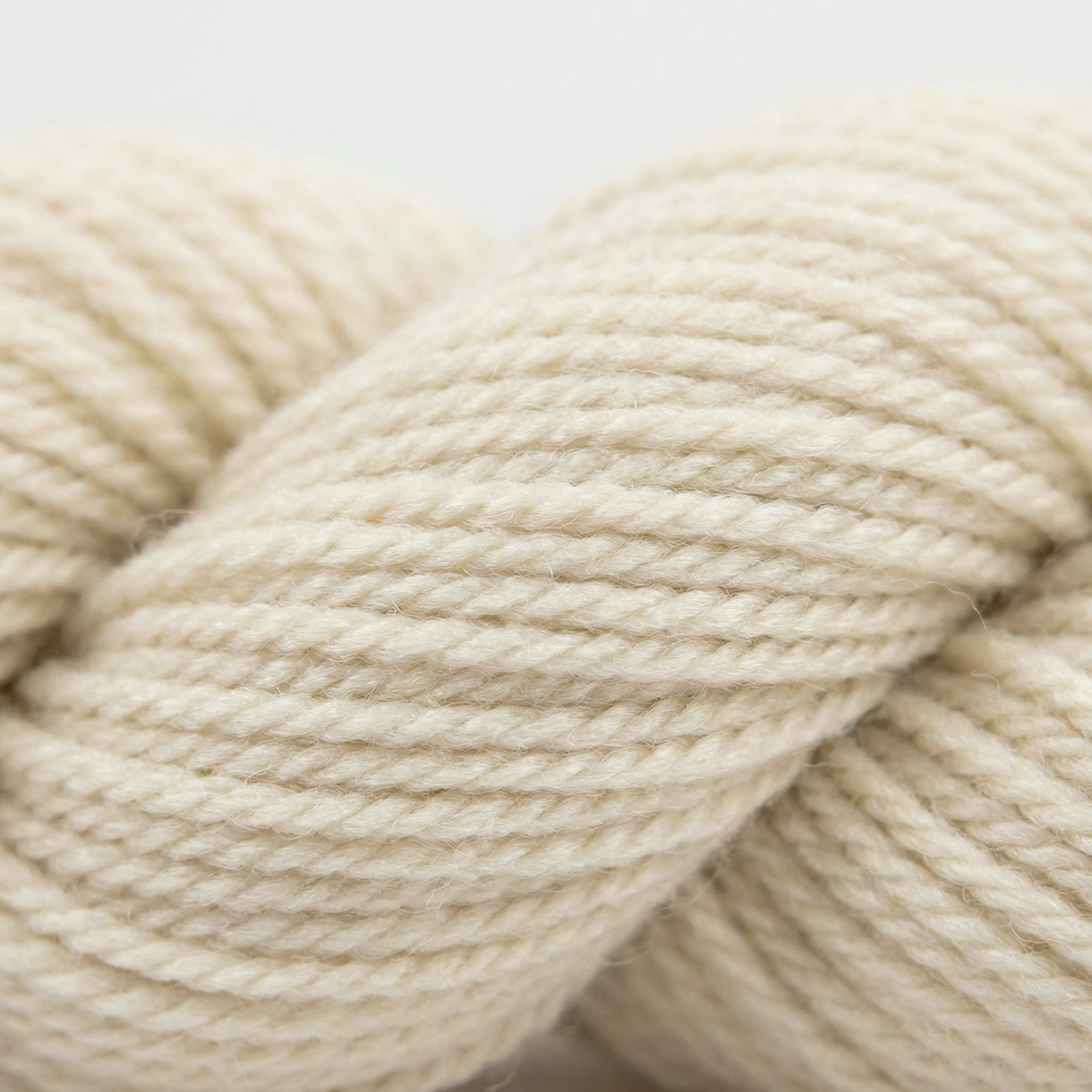 Undyed Blue Faced Leicester (BFL) worsted weight yarn skein, natural cream longwool fiber, clean studio hero on white.