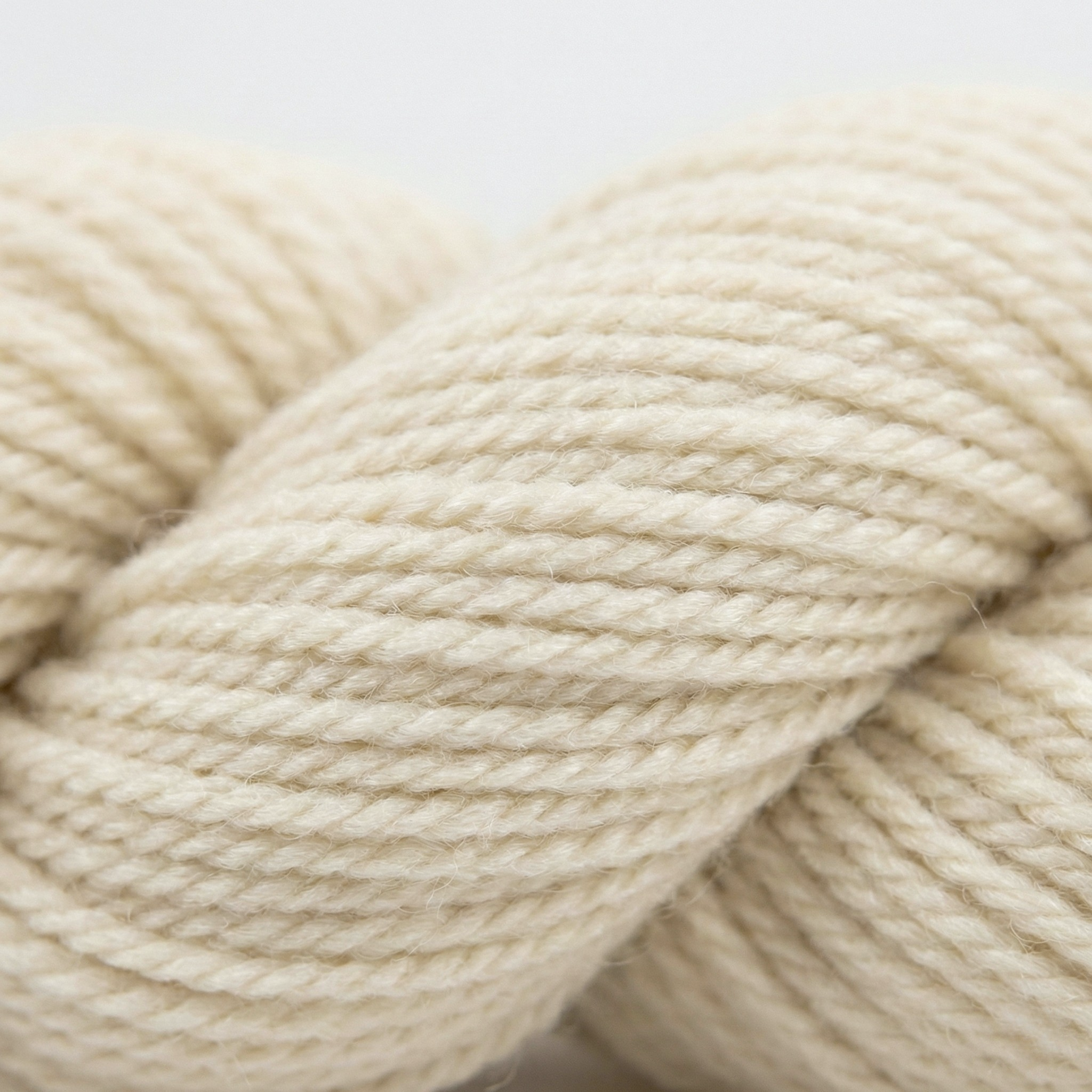 Undyed Blue Faced Leicester (BFL) worsted weight yarn skein, natural cream longwool fiber, clean studio hero on white.
