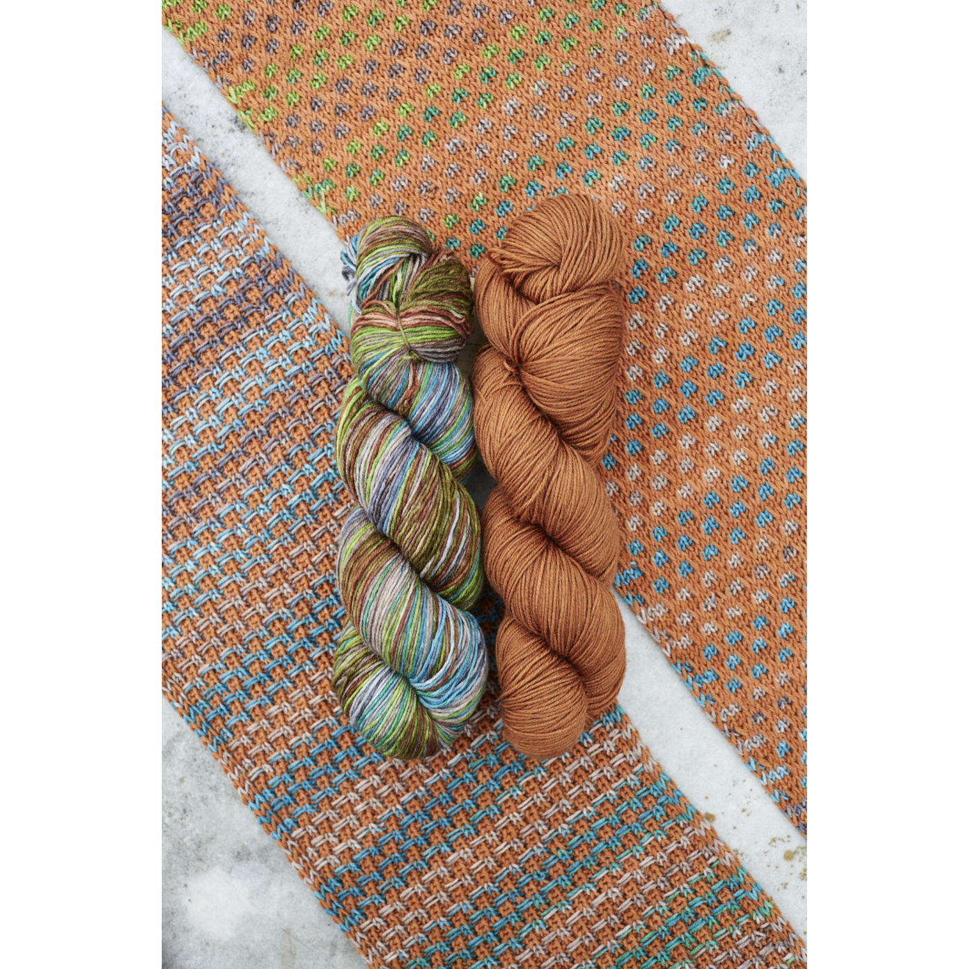 Warm orange‑green Saman Scarf swatch with Uneek 3030 and Harvest Cinnamon fingering Merino skeins.