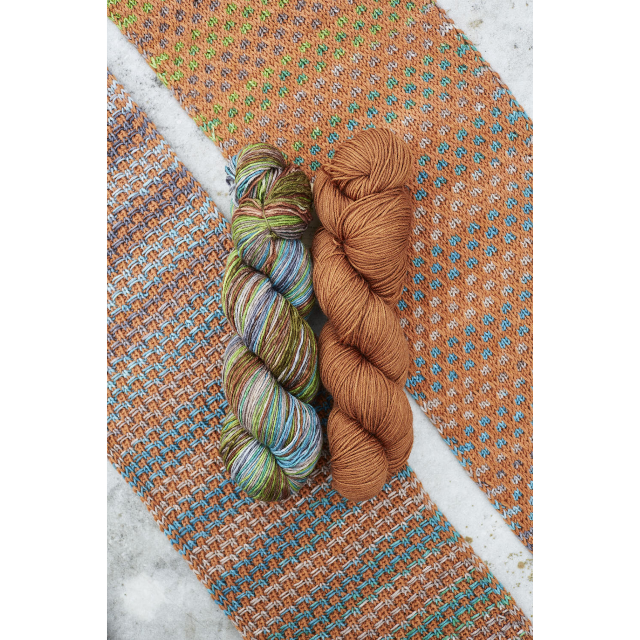 Warm orange‑green Saman Scarf swatch with Uneek 3030 and Harvest Cinnamon fingering Merino skeins.