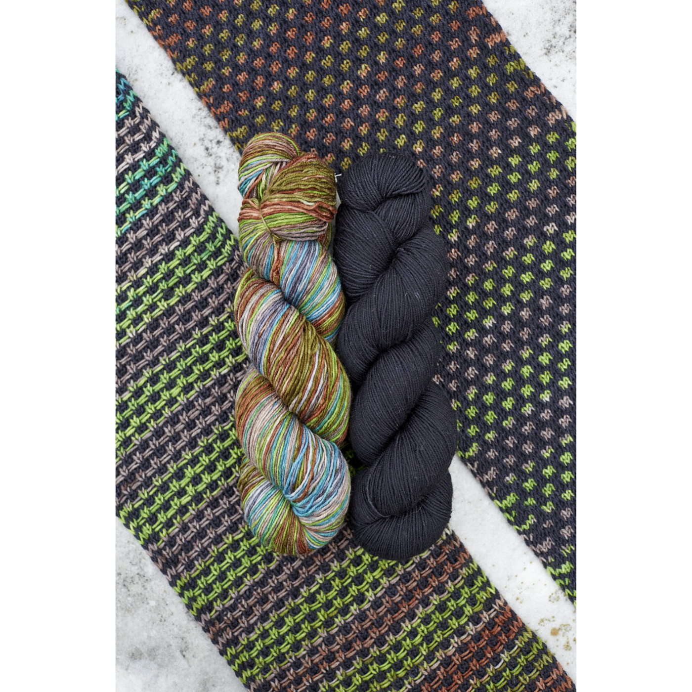 Forest‑inspired Saman Scarf kit swatch featuring Uneek 3030 variegation with deep green Harvest Thuja solid.
