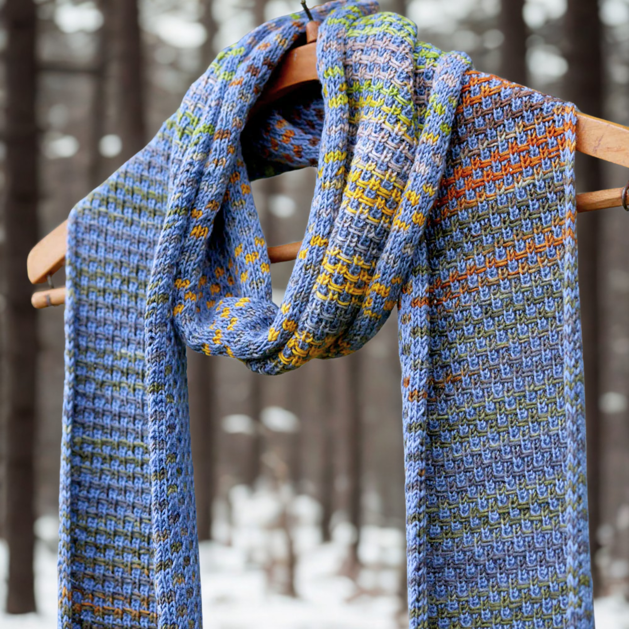 Saman Scarf in Uneek 3001 + Harvest CPC draped on a branch, highlighting vibrant self‑striping colorwork and generous length.