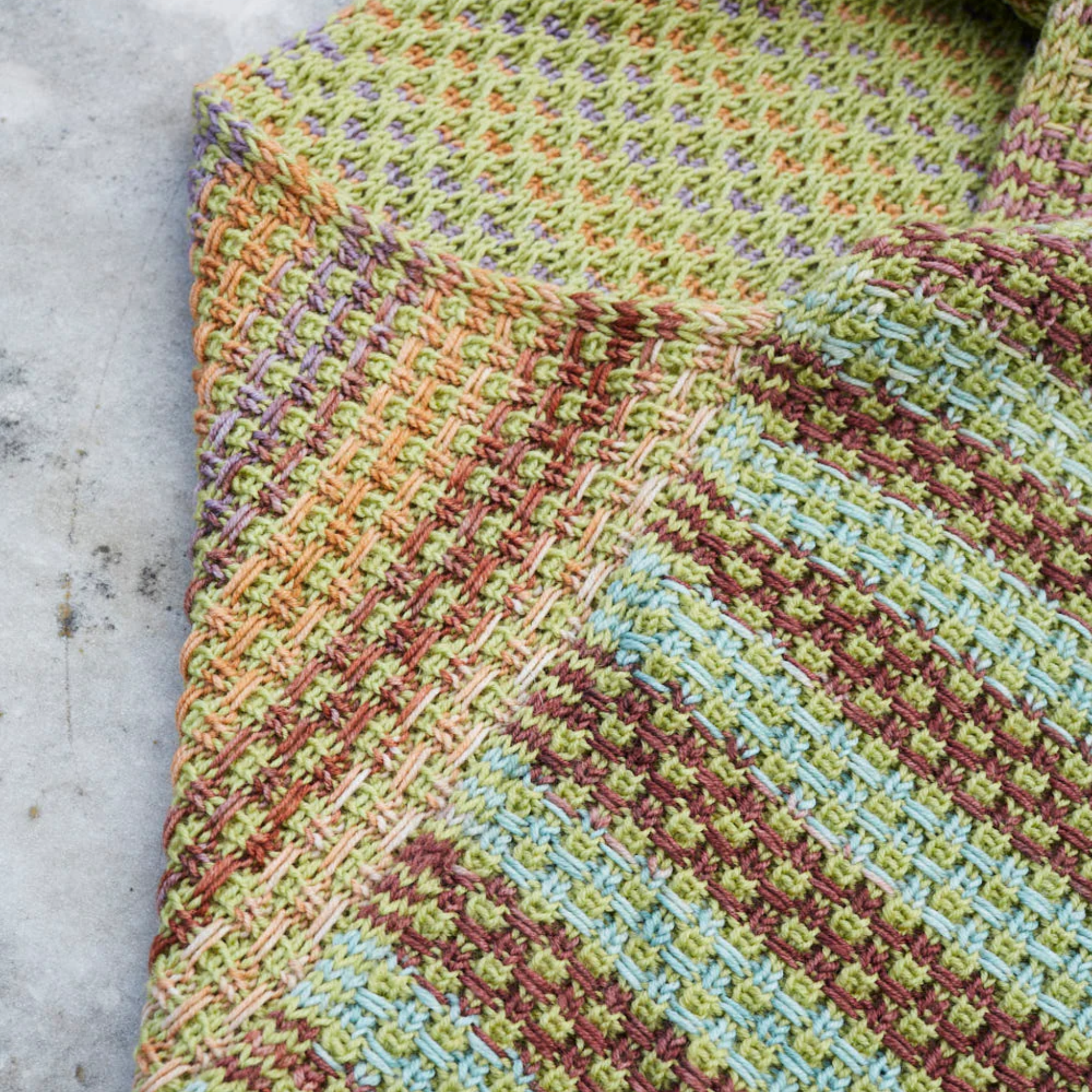 Flat‑lay of the Saman Cowl knit in Harvest Pistachio and Uneek 3036, showcasing fresh green and multicolor stripes.