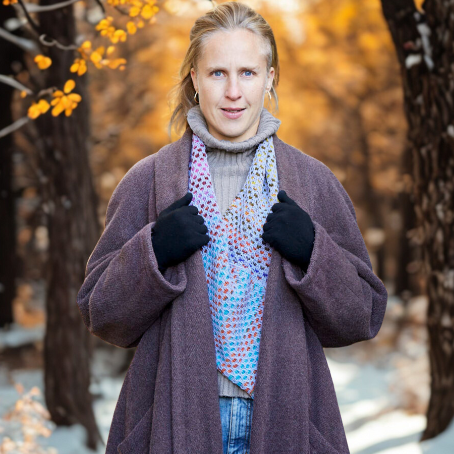 Model wearing the Saman Cowl knit in Urth Uneek 3007 with Harvest Blueberry, styled outdoors among garden greenery.