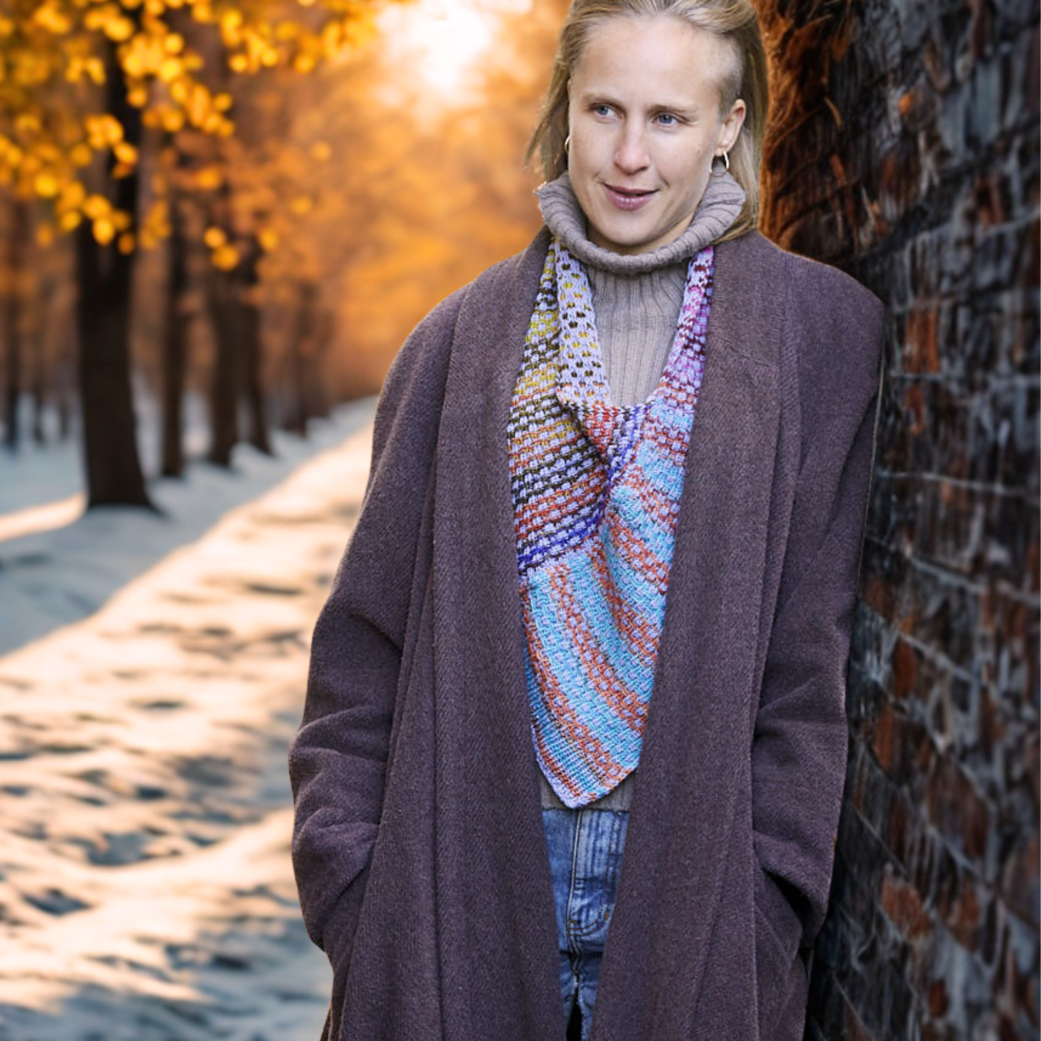 Model wearing the Saman Cowl knit in Urth Uneek 3007 with Harvest Blueberry, styled outdoors among garden greenery.
