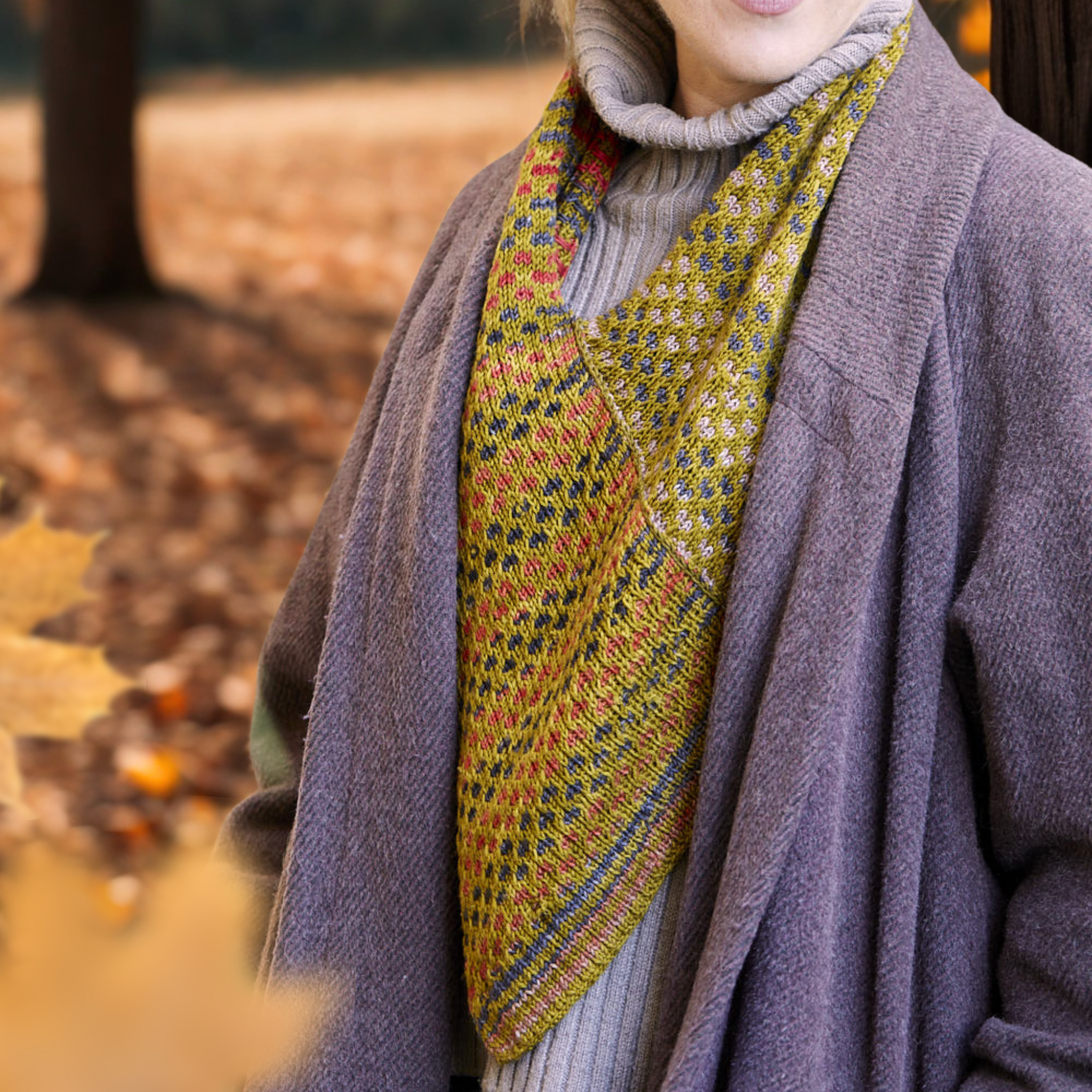 Saman Cowl in Uneek 3021 and Harvest Fig shown in a forest setting, emphasizing its earthy tones.